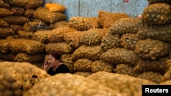 Seorang penjual berbicara melalui telepon genggamnya di dekat tumpukan kentang di Pasar Kramat Jati, Jakarta, pada 6 September 2013. (Foto: Reuters/Beawiharta)