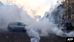 Motorists drive amid clouds of tear gas on the Champs Elysees in Paris, Feb. 12, 2022, as convoys of protesters so called "Caravan of freedom" arrived in the French capital.