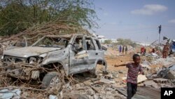 Um rapaz passa pelos destroços de veículo destruído em ataque do grupo extremista al-Shaba à polícia e postos de controlo na periferia da capital Mogadíscio, Somália, 16 de Fevereiro de 2022). (AP Photo/Farah Abdi Warsameh)al-Shabab