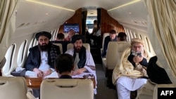 FILE - Afghanistans Foreign Minister Amir Khan Muttaqi, left, Taliban spokesman for the Ministry of Foreign affairs, Abdul Qahar Balkhi, center, and delegates sit on a plane before departing to Oslo, at the Kabul airport in Kabul. (Photo by Afghan Taliban / AFP)