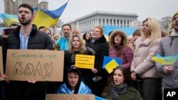 Para warga berkumpul di pusat kota Kyiv menyanyikan lagu kebangsaan Ukraina dalam perayaan Hari Persatuan pada 16 Februari 2022. (Foto: AP/Sergei Grits)