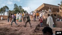 Des hommes de la milice Amhara marchent avec leurs fusils parmi une foule de pèlerins à la veille de la célébration de Genna, le Noël orthodoxe éthiopien, à Lalibela, dans la région nord d'Amhara bordant la région nord du Tigré, le janvier 6, 2022.