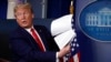 FILE - Then-President Donald Trump holds up papers in the James Brady Press Briefing Room of the White House on April 20, 2020, in Washington.