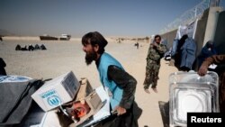 FILE - An UNHCR worker moved aid supplies at a distribution center on the outskirts of Kabul, Oct. 28, 2021. UNHCR said two journalists working for the relief agency and their local colleagues were detained by the Taliban, Feb. 11, 2022.