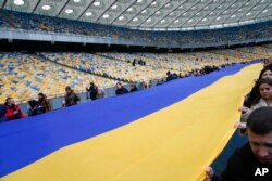 A 200-meter-long Ukrainian flag is unfolded during a Day of Unity event, at the Olympiyskiy stadium in Kyiv, Ukraine, Feb. 16, 2022.