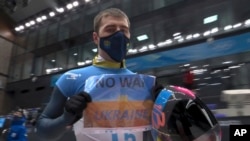 In this frame from video, Vladyslav Heraskevych, of Ukraine, holds a sign that reads "No War in Ukraine" after finishing a run at the men's skeleton competition at the 2022 Winter Olympics, Feb. 11, 2022, in the Yanqing district of Beijing. 
