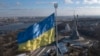 Ukraine's national flag, topped with a trident symbol, flutters above the capital with the Motherland Monument on the right, in Kyiv, Feb. 13, 2022.