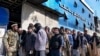 Seorang tentara Taliban berjaga di depan orang-orang yang menunggu untuk masuk ke bank, di Kabul, Afghanistan, 13 Februari 2022. (Foto: AP)