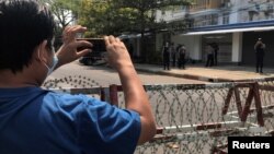 FILE - A journalist and a police officer take pictures of each other during a protest against the military coup, in Yangon, Myanmar, Feb. 23, 2021.