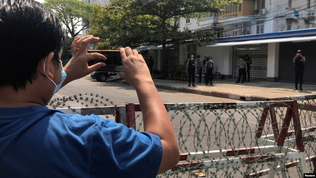 Seorang wartawan dan petugas kepolisian mengambil gambar satu sama lain dalam aksi protes menentang kudeta militer di Yangon, Myanmar, pada 23 Februari 2021. (Foto: Reuters/Stringer)