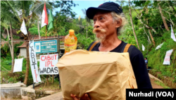 Seniman lukis Yayak Yatmaka menunjukkan bingkisan yang diberikan Ganjar Pranowo usai dibebaskan polisi. (Foto: VOA/Nurhadi)