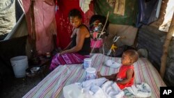 Roselia Jean Charles watches her daughter cry in the shack that serves as their home at the Devirel camp, six months after the 7.2 magnitude earthquake in Les Cayes, Haiti, Feb. 16, 2022. 