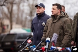 FILE - In this handout photo provided by the Ukrainian Presidential Press Office, President Volodymyr Zelenskyy, right, speaks at a press conference in Kherson, Feb. 12, 2022.