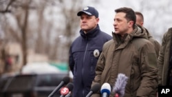 FILE - In this handout photo provided by the Ukrainian Presidential Press Office, Ukrainian President Volodymyr Zelenskyy, right, speaks at a press conference in Kherson, Ukraine, Feb. 12, 2022. 