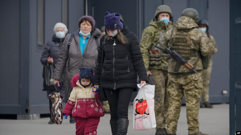 Женщина с ребенком пересекает пункт пропуска в Донбассе, где с одной стороны территория контролируется правительственными силами Украины, а с другой - пророссийскими сепаратистами. Станица Луганская. 11 февраля 2022г.