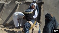 FILE - Taliban members stand guard near the rubble of a suspected Islamic State hideout following an operation against Islamic State-Khorasan, the local chapter of the jihadist group, in Kandahar, Afghanistan, Nov. 15, 2021. 