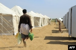 FILE - Displaced Yemenis return to their tents with aid donated by a Kuwaiti charitable organization on the outskirts of the northeastern city of Marib, on Jan. 1, 2022