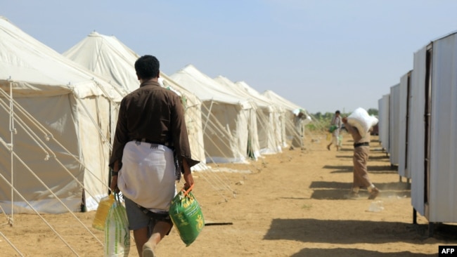 Seorang warga Yaman kembali menuju tenda pengungsian, yang dibangun dari dana sumbangan lembaga donor Kuwait, pada 1 Januari 2022. Kamp pengungsian tersebut terletak di sebelah timur laut Kota Ma'rib, Yaman. (Foto: AFP)