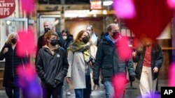 FILE - Shoppers wear masks while walking through an indoor market in New York City, Feb. 9, 2022.