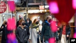 FILE - Shoppers wear masks while walking through an indoor market in New York City, Feb. 9, 2022.