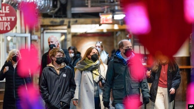 FILE - Shoppers wear masks while walking through an indoor market in New York City, Feb. 9, 2022.
