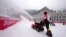 Workers clear snow from inside the finish area of the alpine ski venue speed course at the 2022 Winter Olympics, Feb. 13, 2022, in the Yanqing district of Beijing. 