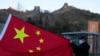 A visitor holds the Chinese flag near the Badaling section of the Great Wall of China on the outskirts of Beijing on Feb. 8, 2022.