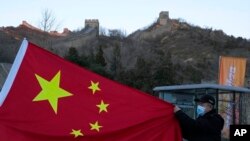 A visitor holds the Chinese flag near the Badaling section of the Great Wall of China on the outskirts of Beijing on Feb. 8, 2022.