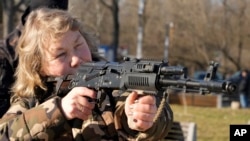A woman practices using a Kalashnikov assault rifle as members of a Ukrainian far-right group train, in Kyiv, Ukraine, Feb. 13, 2022. 
