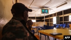 A patron watches on a television set from a coffee shop in Ouagadougou on Feb. 16, 2022 the inauguraiton ceremony of Lieutenent-Colonel Paul-Henri Sadaogo Damiba as Burkina faso President.