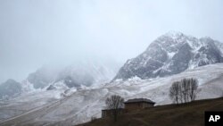 Una casa se ve a la sombra de montañas nevadas en el distrito predominantemente tibetano de Garze, en la provincia china de Sichuan, el 5 de febrero del 2022. 