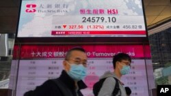 People walk past a bank's electronic board showing the Hong Kong share index at Hong Kong Stock Exchange Monday, Feb. 14, 2022. Asian stock markets fell Monday and oil prices rose amid concern about a possible Russian invasion of Ukraine. (AP Photo/Vincen