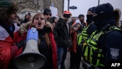 A woman faces off with police during a protest over pandemic health rules outside the parliament of Canada in Ottawa on February 11, 2022. (Photo by Ed JONES / AFP)