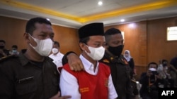 Herry Wirawan (tengah) dikawal sebelum diadili di pengadilan di Bandung, Jawa Barat pada 15 Februari 2022, di mana ia kemudian dijatuhi hukuman penjara seumur hidup atas pemerkosaan terhadap 13 siswa, semuanya di bawah umur. (Foto: AFP/Timur Matahari)