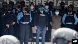 Former Honduran President Juan Orlando Hernandez, center in chains, is shown to the press at the Police Headquarters in Tegucigalpa, Honduras, Tuesday, Feb. 15, 2022. (AP Photo/Elmer Martinez)