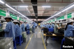 中國廣東東莞一家生產移動遊戲控制器的工廠工人在生產線上工作。（2021年12月7日）