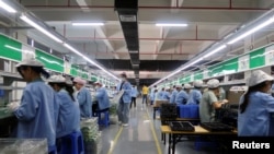 中国广东东莞的工人为一家美国公司的RiotPWR移动游戏控制器在生产线上工作。（2021 年 12 月 7 日）