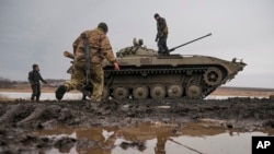 Ukrainian servicemen walk on an armored fighting vehicle during an exercise in a Joint Forces Operation-controlled area in the Donetsk region, eastern Ukraine, Feb. 10, 2022.