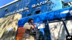 Seorang kombatan Taliban berjaga di luar sebuah bank di Kabul, Afghanistan, 13 Februari 2022. (Foto: Hussein Malla/AP Photo)