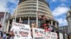 Para pengunjuk rasa memegang spanduk mendukung iring-iringan mobil yang menghalangi Parlemen Selandia Baru, di Wellington, Selasa, 8 Februari 2022. (Mark Mitchell/New Zealand Herald via AP)