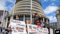 Para pengunjuk rasa memegang spanduk mendukung iring-iringan mobil yang menghalangi Parlemen Selandia Baru, di Wellington, Selasa, 8 Februari 2022. (Mark Mitchell/New Zealand Herald via AP)