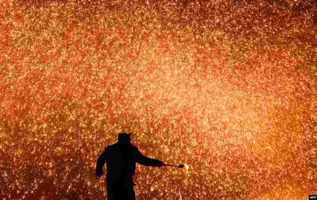 A blacksmith throws molten metal to create a shower of sparks, on the eve of the Lantern Festival, which marks the end of Lunar New Year celebrations, at a park in Beijing, China.