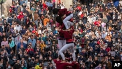 Spectators watch as participants in the "diada Castellera'' try to complete a human tower during the Saint Eulàlia celebrations in Barcelona, Spain, Feb. 11, 2022. 