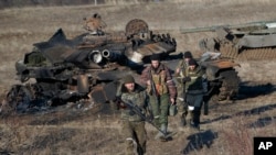 FILE - Russia-backed separatists walk after inspecting destroyed Ukrainian army tanks near Lohvynove, Ukraine, Feb. 22, 2015. A peace accord for eastern Ukraine has remained stalled for years, but it has come into the spotlight again amid a Russian military buildup near Ukraine.