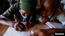 A classmate helps Priscilla Sitienei complete a class assignment, January 25, 2022. REUTERS/Monicah Mwangi
