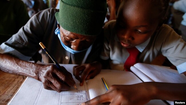 A classmate helps Priscilla Sitienei complete a class assignment, January 25, 2022. REUTERS/Monicah Mwangi