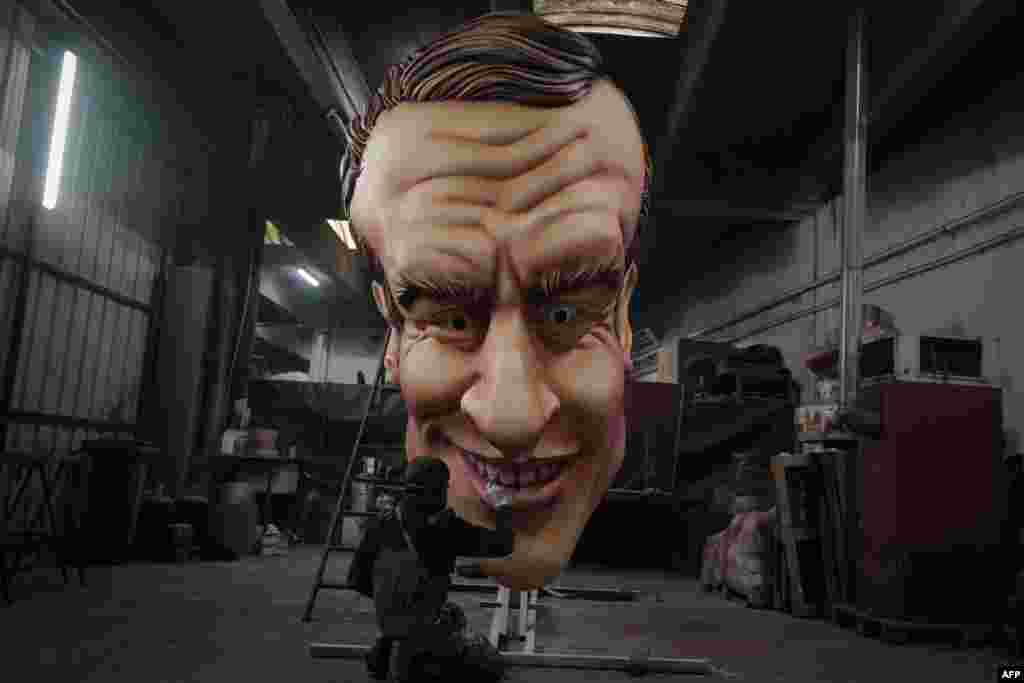 An artist works on a giant caricature of the head of French President Emmanuel Macron created for the upcoming 2022 Nice Carnival, in the French riviera city of Nice.