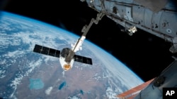 In this Friday, April 17, 2015 file photo, the Canadarm 2 reaches out to capture the SpaceX Dragon cargo spacecraft for docking to the International Space Station. (AP Photo/NASA)