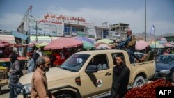 Anggota pasukan Taliban yang berada di atas mobil pick-up berkeliling di area pasar yang dipenuhi oleh para warga Afghanistan di Kote Sangi area, Kabul, pada 17 Agustus 2021. (Foto: AFP/Hoshang Hashimi)