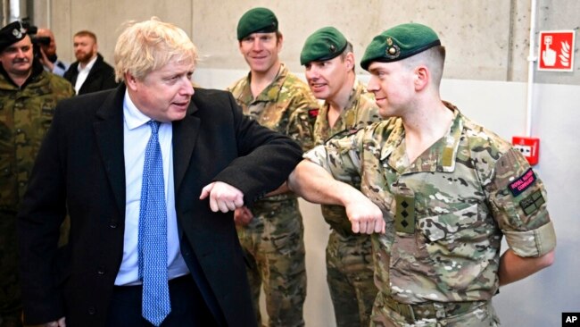 British Prime Minister Boris Johnson meets a member of the British Marines during a visit with his Polish counterpart, Mateusz Morawiecki, at the Warszawska Brygada Pancerna military base near Warsaw, Poland, Feb. 10, 2022.
